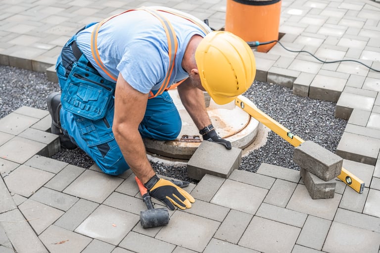 Laying interlocking paving stones around sewer manhole cover